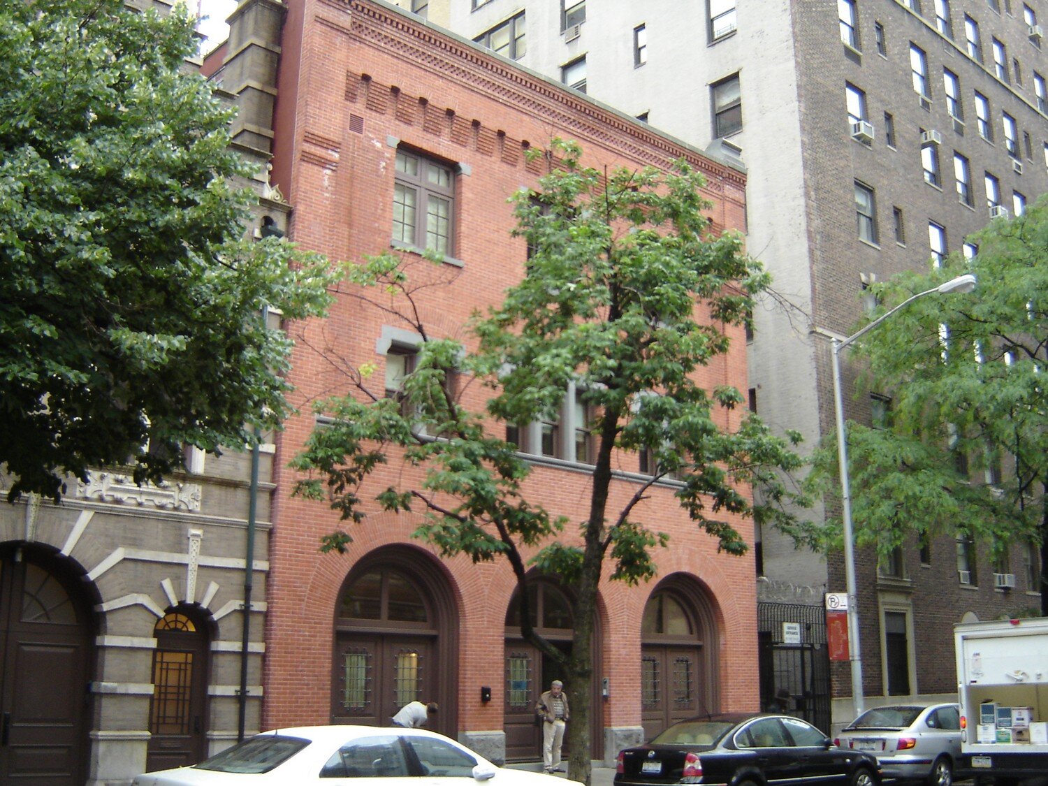 Brick townhouse facade on a tree-lined New York City block
